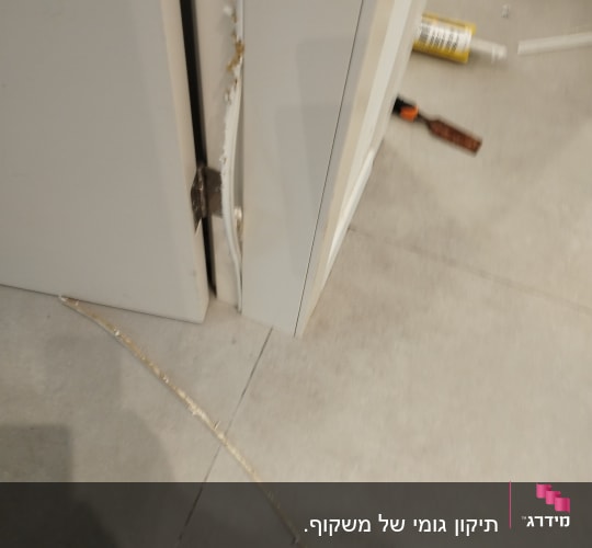 דלת לבנה עם מסגרת פגומה וכלי עבודה על הרצפה
